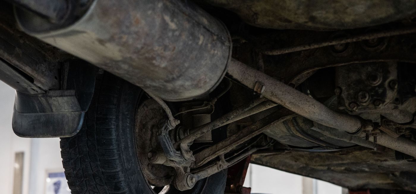 Licensed stock photograph: the underside of a vehicle raised on a lift, showing exhaust, control arms and a leaf spring.